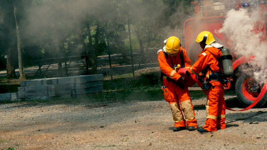 难的消防员用水管化学泡沫喷洒剂发动机与火焰战斗的消防员Fierman戴硬帽身穿防火灭器方面的营救训练制服主安全图片
