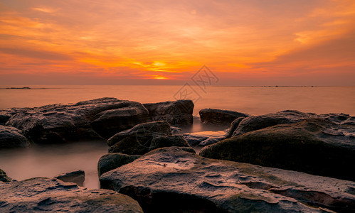 海滨日落时在石滩上的岩美丽海边夕阳天紫光海与空黄昏时的热带海风云天空和日落抽象背景平静放松生命景观港口黎明图片