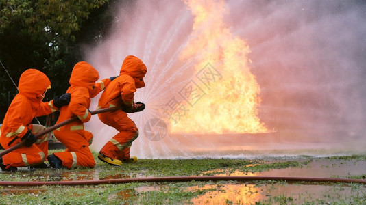 烧伤消防员用水管化学泡沫喷洒剂发动机与火焰战斗的消防员Fierman戴硬帽身穿防火灭器方面的营救训练制服援面具图片