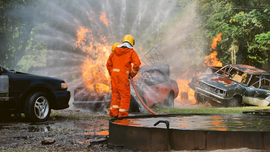 英雄安全的帽子消防员用水管化学泡沫喷洒剂发动机与火焰战斗的消防员Fierman戴硬帽身穿防火灭器方面的营救训练制服图片