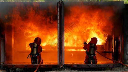 消防员用水管化学泡沫喷洒剂发动机与火焰战斗的消防员Fierman戴硬帽身穿防火灭器方面的营救训练制服烧伤抽烟头盔图片