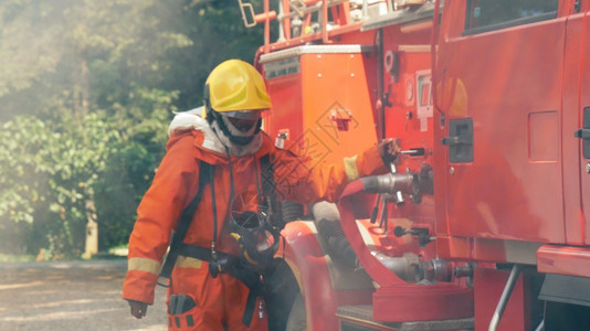 热工人消防员用水管化学泡沫喷洒剂发动机与火焰战斗的消防员Fierman戴硬帽身穿防火灭器方面的营救训练制服红色的图片