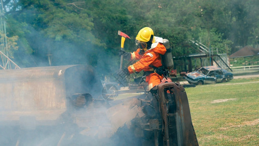 红色的危险火花消防员用水管化学泡沫喷洒剂发动机与火焰战斗的消防员Fierman戴硬帽身穿防火灭器方面的营救训练制服图片