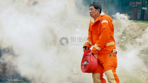 救援消防员用水管化学泡沫喷洒剂发动机与火焰战斗的消防员Fierman戴硬帽身穿防火灭器方面的营救训练制服帽子氧图片