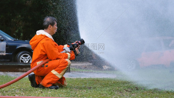 战斗机热的危险消防员用水管化学泡沫喷洒剂发动机与火焰战斗的消防员Fierman戴硬帽身穿防火灭器方面的营救训练制服图片