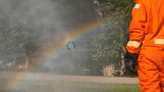 红色的消防员用水管化学泡沫喷洒剂发动机与火焰战斗的消防员Fierman戴硬帽身穿防火灭器方面的营救训练制服帽子难的图片