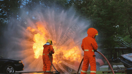 男人套装保护消防员用水管化学泡沫喷洒剂发动机与火焰战斗的消防员Fierman戴硬帽身穿防火灭器方面的营救训练制服图片