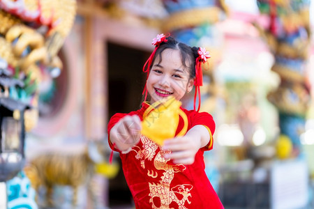 假期女重点穿着红色传统青山装饰焦点的亚洲小可爱女孩在泰兰神庙举办新年庆典展示金钱袋以备新年盛会时使用图片