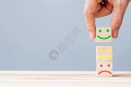 评估优秀的木头情感服务评级排名客户审查满意度和反馈概念手持微笑的脸符号在木立方块上图片