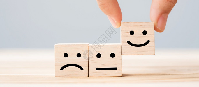 情感服务评级排名客户审查满意度和反馈概念手持微笑的脸符号在木立方块上保持乐趣堵塞图片