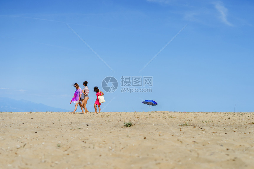 太阳闺蜜游客树上年轻女子在夏春沙滩上行走或秋阳光明媚的日子在空旷海滩上与蓝天对立图片