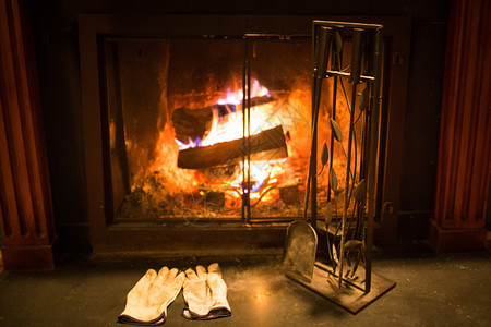 自然热燃烧舒适的壁炉用工具和手套清空的拳击和手套充耳燃烧舒适的壁炉用工具和手套黑暗的图片