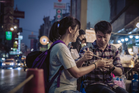 快速地亚洲情侣在街头食物市场吃东西晚上在Bangkok的Yaowarat路城旅游客辛辣的健康图片
