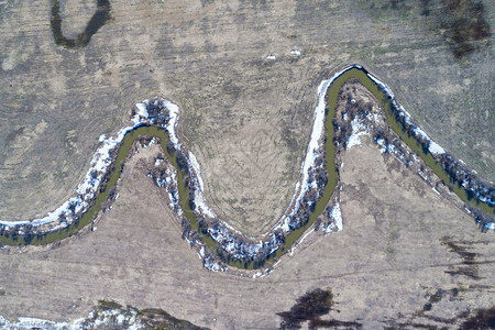 跑步遥远超过冬季末的农田中流经一条河的空中景象图片