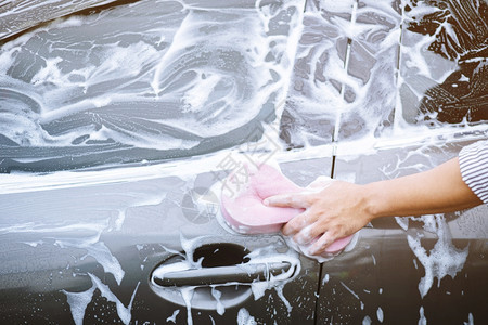 城市的男子用手持粉色海绵洗车清洁工人运输图片