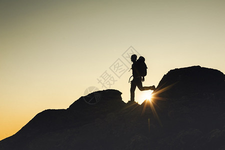 积极的最佳爬一名男子在日落时走过蒙塔山的一图片
