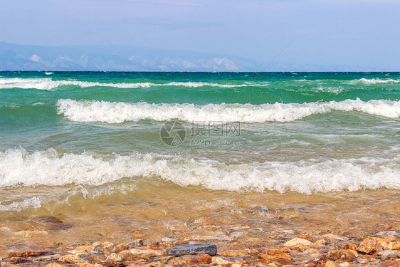 俄罗斯西伯利亚夏季旅游节奥卡孔岛BaikalPebble湖海滩泊纯绿水和蓝天的色空上出现明亮风雨天气和海浪的景象夏天自然力量图片