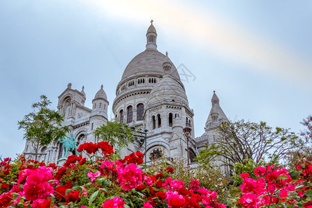 正面假期红色的巴黎圣心教堂附近的法国阴云之夜花朵和红玫瑰在夏天晚上圣心教堂前的额花朵中盛放红玫瑰图片
