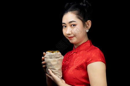 服装亚洲年轻穿红礼服的亚洲女传统青森在黑背上袋中拿着金币的黑衣长袍女孩新年概念昂微笑图片