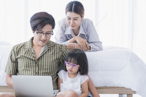 经过快乐的趣一个温暖家庭在节假日共度一个温暖的家庭在一起时间小女孩正在使用笔记本电脑在线学习图片