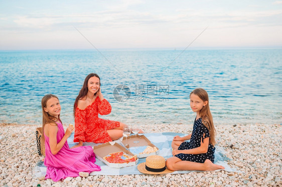 父母快乐的亲和孩子在海滩野餐上野餐的一家庭篮子假期图片