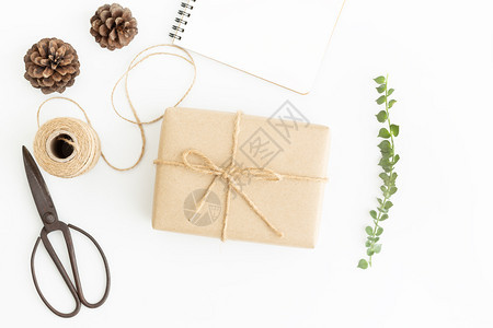 礼物白色背景的品包和旧剪刀手制附件和棕色礼品盒的平面照片躺着弓图片