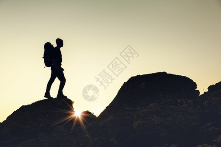 自然顶峰高的一名男子在日落时走过蒙塔山的一图片