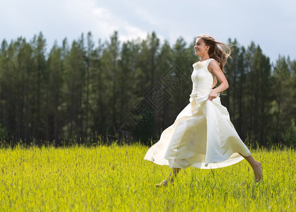 白色的穿着裙子女孩在田里跳跃春天活力图片