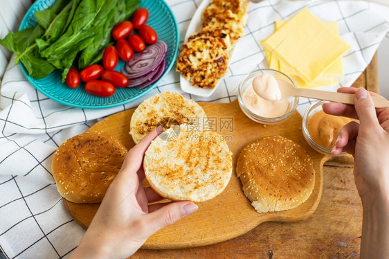 配料餐厅准备制作汉堡的所有原料面包炸肉排奶酪沙拉番茄酱汁顶视图girlrsquos手拿汉堡卷准备制作汉堡的所有原料面包番茄酱汁手图片