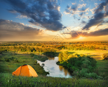 日落时自然风景中的橙色帐篷图片