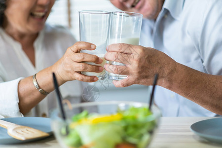 亚洲人健康的年老人夫妇享受喝杯玻璃新鲜牛奶的快乐微笑老年男女早上吃餐开心愉快笑声掌高级的拥抱背景图片