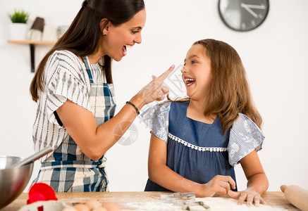 年轻的爱母亲和女儿在厨房玩得开心学习做蛋糕的一拍镜头情感图片