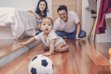 人们在室内亚洲男婴爬到木地板上父母在卧室的里家庭生活方式概念中在父亲和母的楼上卷曲图片