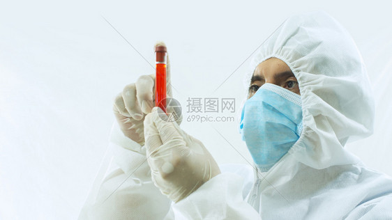 商业管子戴口罩和白色生物防护服的医用手拿着血样试管在白色背景上专心地盯着它戴口罩和生物防护服的医用手拿着血样试管在白色背景上专心图片