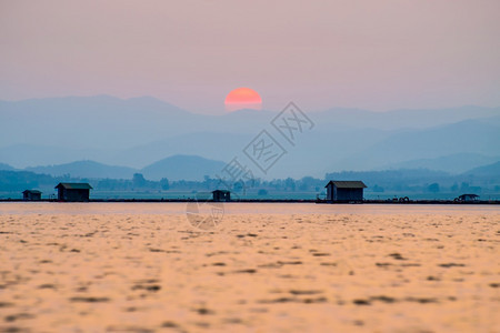 当地的美丽自然景观橙色太阳在红的天空光下在水湖蓝色山背景在日落时剪影鱼农场笼子村生活方式在Krasiao大坝素攀武里泰国太阳在山图片