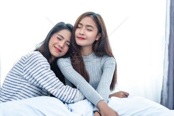 两个亚洲女者在卧室美容概念中拥抱在一起快乐的生活方式和家庭甜蜜的主题Cushion枕头元素和窗幕背景爱人的情场景朋友们亚洲人美丽图片