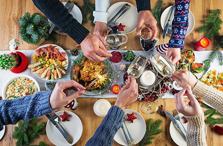 平坦的圣诞晚餐桌配有火鸡装饰着明亮的锡轮和蜡烛炸鸡餐桌家庭晚风景手放在架子上蔬菜派对图片