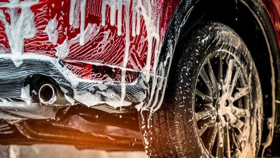 抽象的红色紧凑型SUV车带有运动和现代设计洗的红色小型SUV车用肥皂洗现代设计涤包括白泡沫汽车护理服务业概念在玻璃蜡和涂层汽车前图片