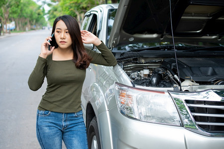 路边愤怒的亚洲妇女在街头汽车故障后使用移动电话求救车辆发动机问题概念或意外事故以及专业技工的紧急帮助在交通失灵之后使用手机求助电图片