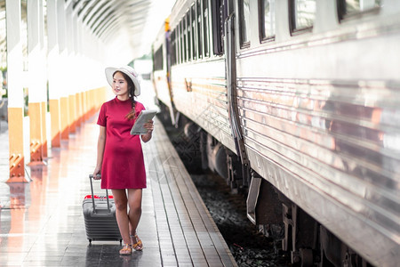 幸福旅游女士在火车站旅行时怀着红色穿衣的亚洲妇女乘红色手提箱旅行在夏季带背包的旅行者泰国假日概念图片