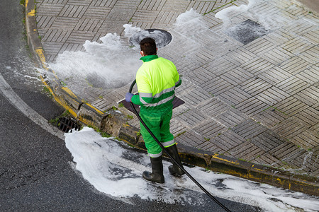 资源看守人用水和洗涤剂在人行道上打扫水和清洁剂的工人维护或清洁概念湿的图片