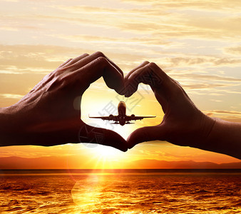 象征心爱团圆形的人之手在天与起飞机相伴的天空背景下心形的爱人之手图片