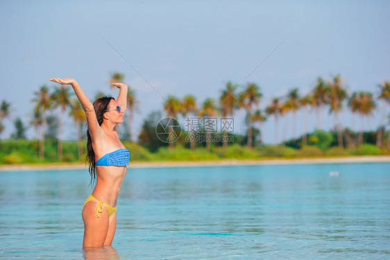 目的地夏天快乐女子在浅水海滩上玩得开心在海滩上穿绿礼服的年轻时尚女子太阳图片
