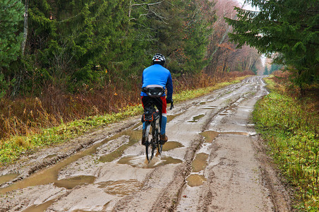 夏天骑自行车的人在森林里走的路线在雨水坑骑自行车的人之后满是秋黄的叶子环境湿图片