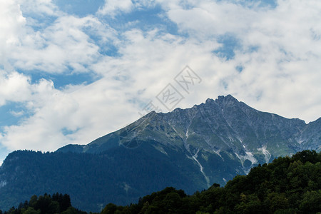 夏天阿尔卑斯山峰顶前方有森林和深蓝天空速连科瑞士图片