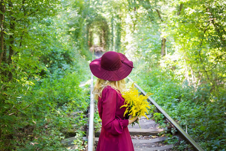 自然花的戴着一顶帽子女孩带着一束黄色花朵美丽图片