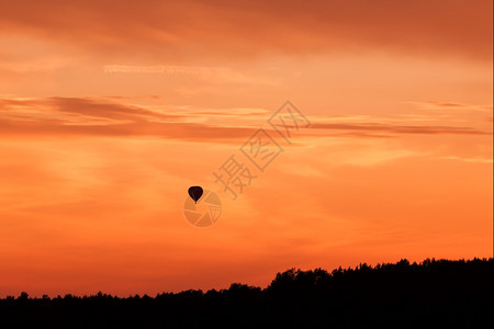 篮子平静的漂浮在橙色日落天空飞行的热气球图片