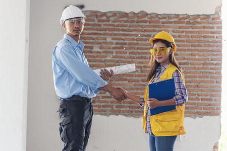 介绍土木建筑工程师团队一起握手在建筑工地戴作头盔人行业项目作程师团队合两个亚洲工程师团队一起握手训练经理图片
