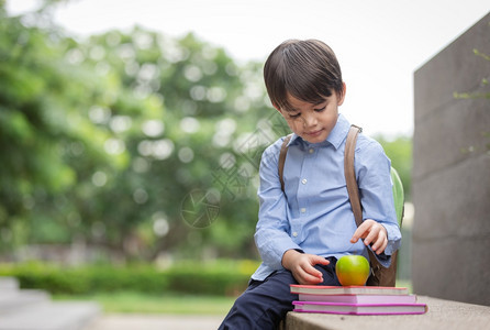 户外拿着苹果准备上学的小男孩图片