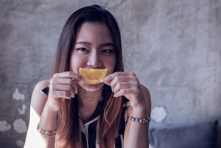 亚洲人一个美女的肖像微笑着拿一块橙子右侧有复制空间在右手边一顿饭水果图片